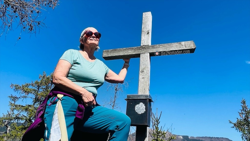 die Nomadin genießt die Aussicht beim Gipfelkreuz